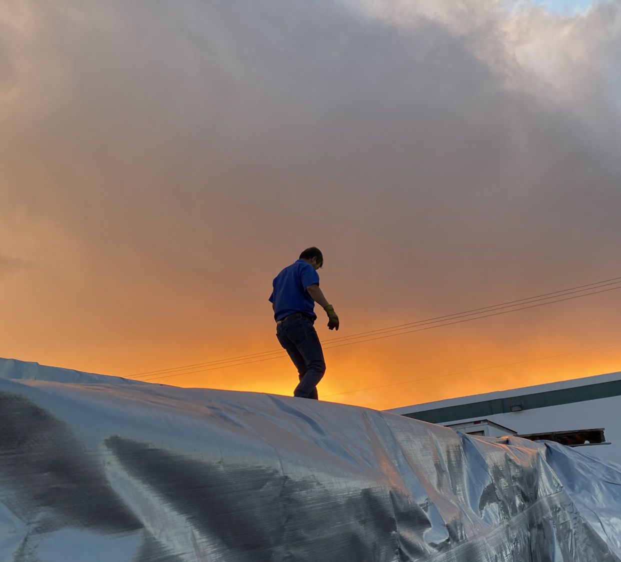 An S.K. Machinery Moving crew member securing a wrapped load at sunset