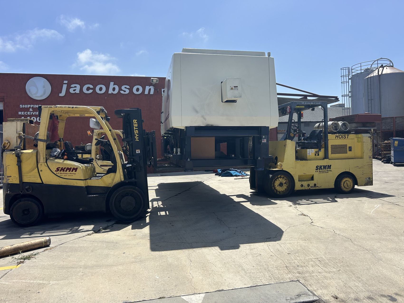 S.K. Machinery Moving crew moving a large industrial machine with two forklifts