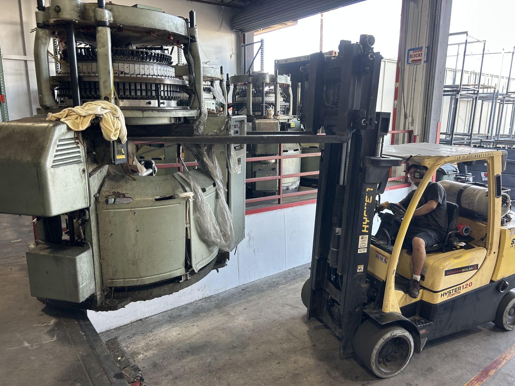 S.K. Machinery Moving crew relocating an industrial textile machine by forklift