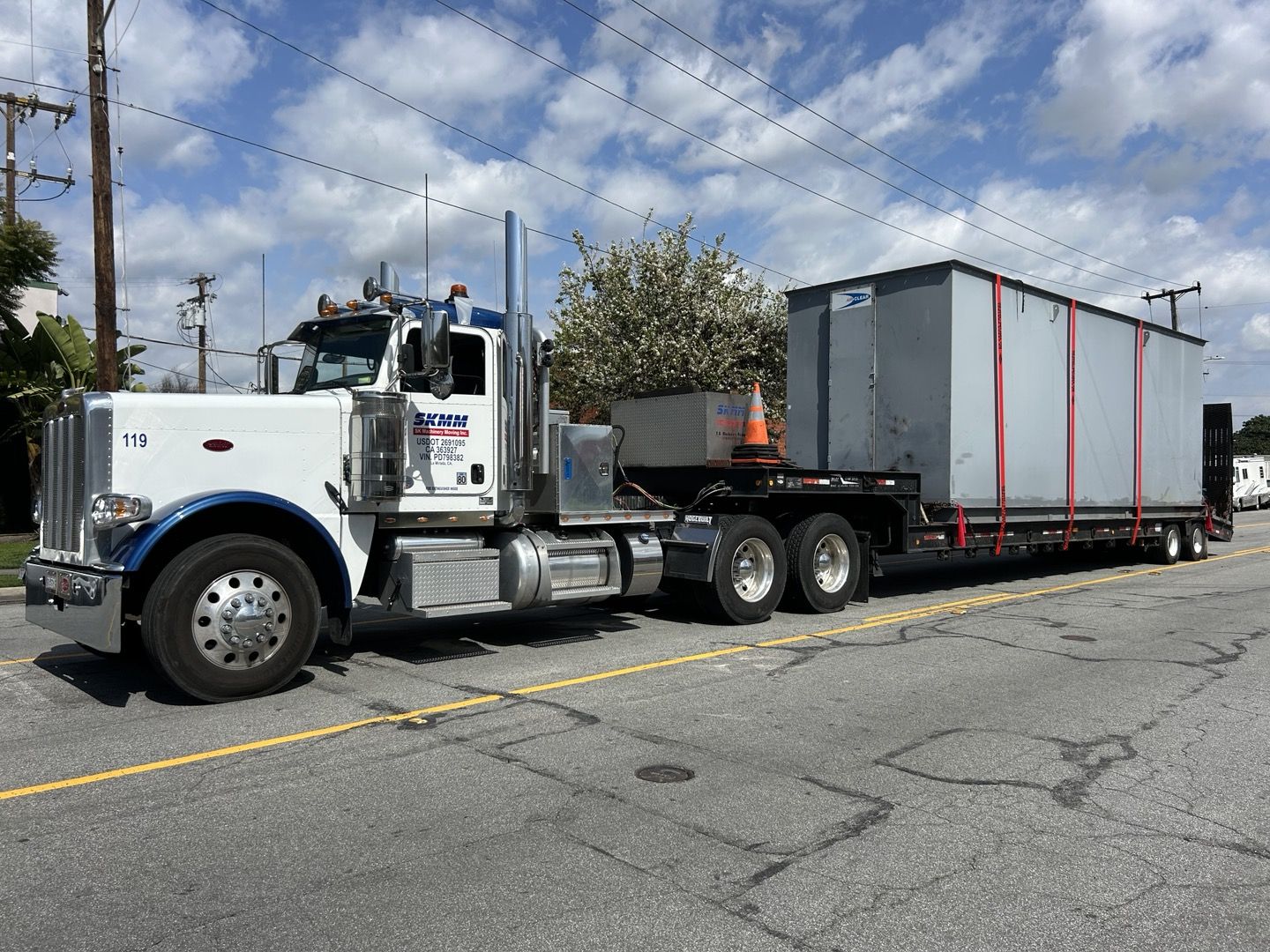S.K. Machinery Moving flatbed truck transporting a large wrapped dry cleaning machine