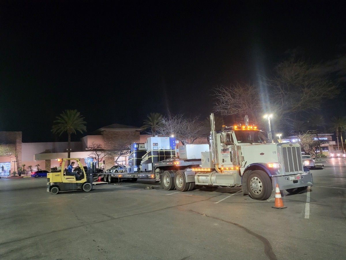 S.K. Machinery Moving truck and forklift loading production equipment at night